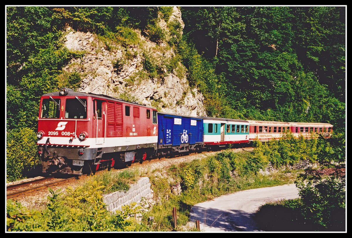 2095 008 fährt mit R6926 am 10.08.2000 bei Koglhof Richtung Waidhofen. Viele Züge auf der Ybbstalbahn wurden im Sommer mit einem Fahrradtransportwagen verstärkt. Nachdem die Ybbstalbahn eingestellt wurde befindet sich hier nun auf der ehemaligen Bahntrasse ein Radweg.