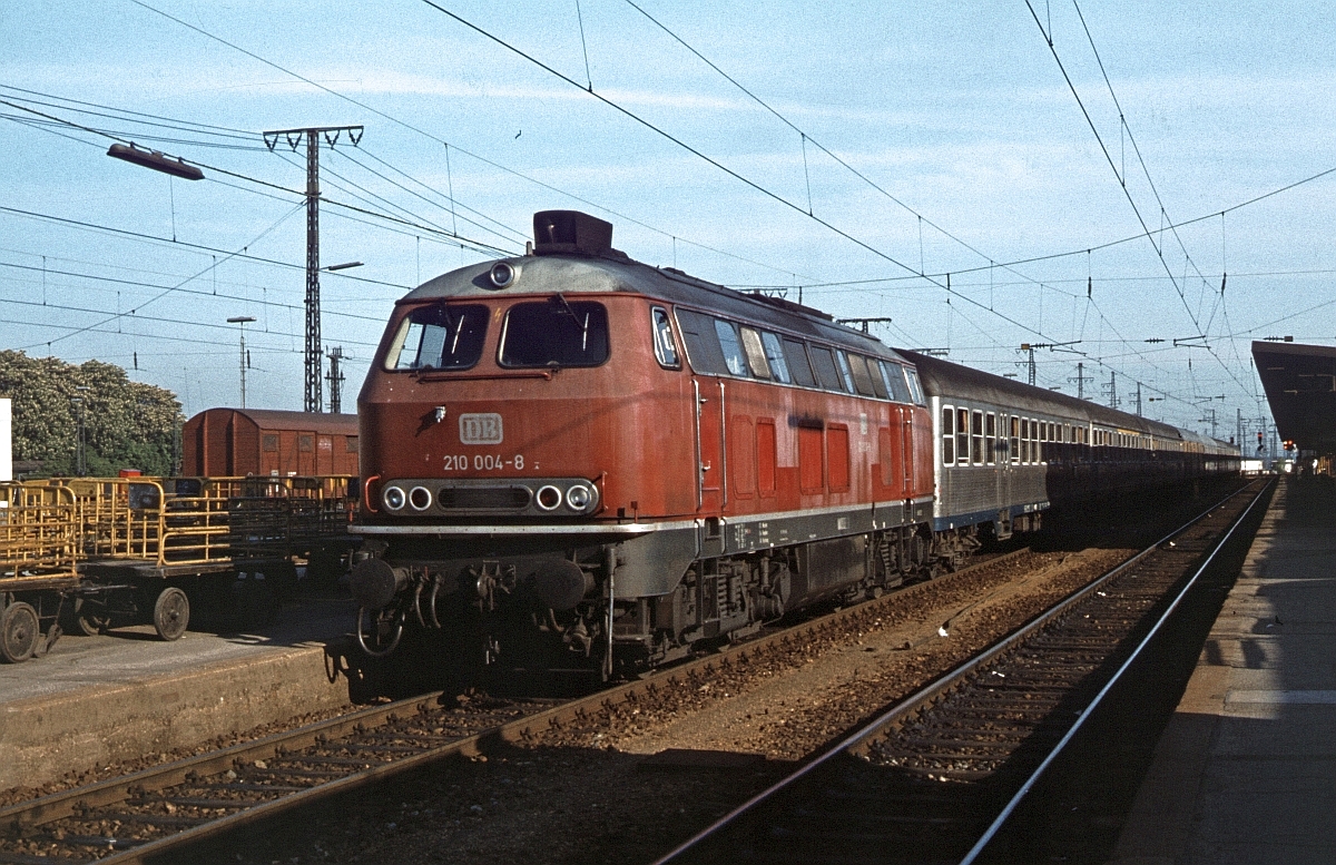 210 004 im Mai 1979 vor einem Eilzug nach Lindau in Augsburg Hbf. 210 004 war die einzige, die noch mit 210-Beschriftung wieder dem ozeanblau-beigen Farbtopf  entstieg  (obwohl man ihr die Gasturbine bereits ausgebaut hatte), alle anderen wurden bei dieser Gelegenheit in 218.9 umgezeichnet.