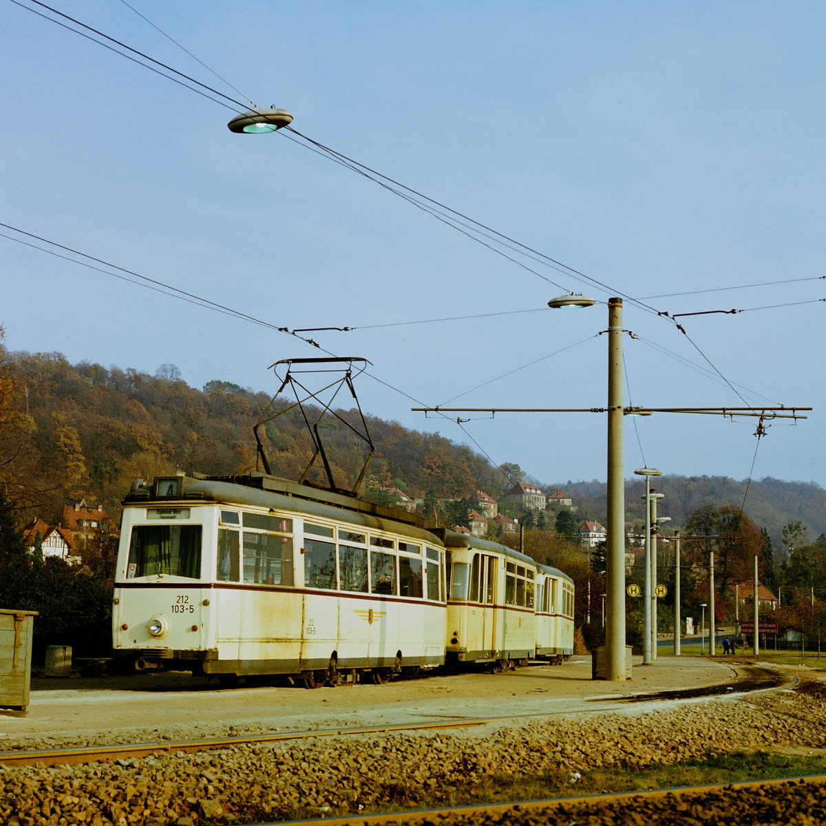 21.10.1984. Ein Zug der Linie 4 pausiert an der Endhaltestelle in Pillnitz.Text des Transparentes im Hintergrund:  Unter Führung der SED weiter auf dem bewährten Kurs . Tw 212 103 stammt aus der Serie (101 bis 116) die 1954 in Werdau gebaut worden ist. Die Beiwagen stammen aus Gothaer Produktion. In der links angeschnittenen Kiste befindet sich Bremssand.
