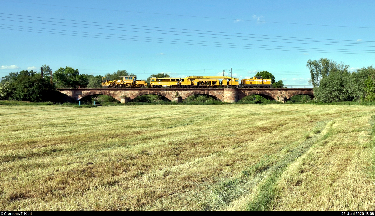 212 192-9 (V 100 2192 | DB V 100.20) der Wiebe Holding GmbH & Co. KG überquert, zusammen mit der unternehmenseigenen Universal-Gleisstopfmaschine Plasser & Theurer UNIMAT 09-32 4S  Bremen  (99 80 9124 007-2 D-HFW) sowie der Schotterplanier- und Profilierungsmaschine Plasser & Theurer SSP 110 SW (Nr. 739 | 99 80 9425 009-4 D-HFW), die Saaleaue bei Angersdorf auf der Bahnstrecke Halle–Hann. Münden (KBS 590) Richtung Halle (Saale).
[2.6.2020 | 18:08 Uhr]
