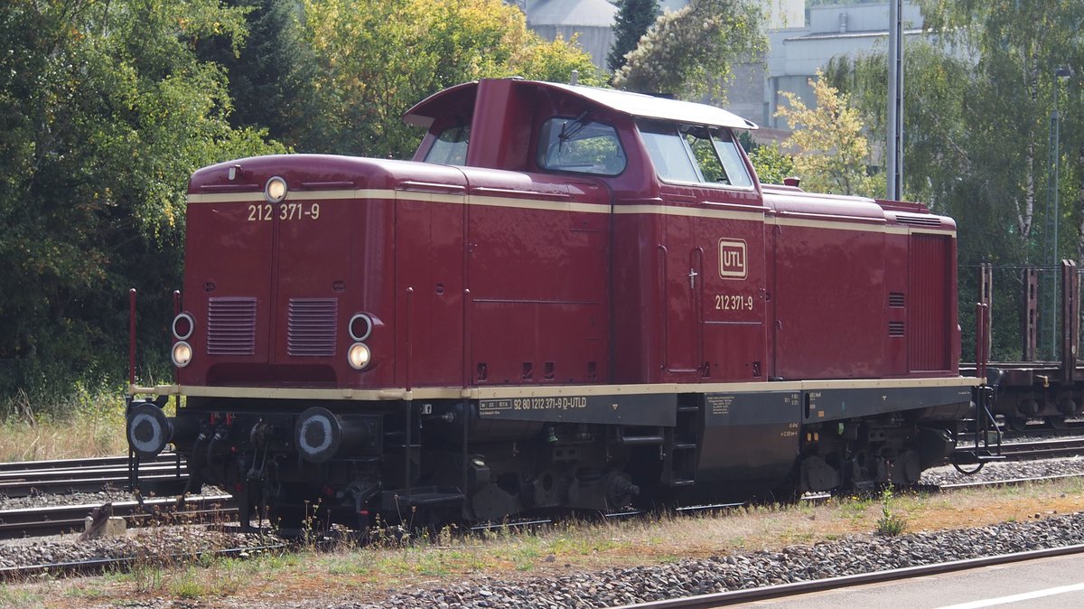212 371-9 der UTL (Umwelt- und Transportlogistik GmbH, Singen (Hohentwiel) ) im Bahnhof Schelklingen. Gebaut 1965 und an die DB ausgeliefert erhielt sie die Nummer  V 100 2371 . 1968 umgezeichnet blieb sie bis 2004 in DB-/ Railion-Diensten. 2006 wurde die Lok ausgemustert, kam nach Ungarn und von dort über die ALS zur UTL.
An diesem Tag hatte die Lok einen Rungenwagen-Zug in zwei Teilen von Münsingen nach Schelklingen gebracht und dort zu einem Ganzzug von gut 400 m Länge zusammengestellt.
Aufnahmedatum: 13.09.2018; 15:20 Uhr