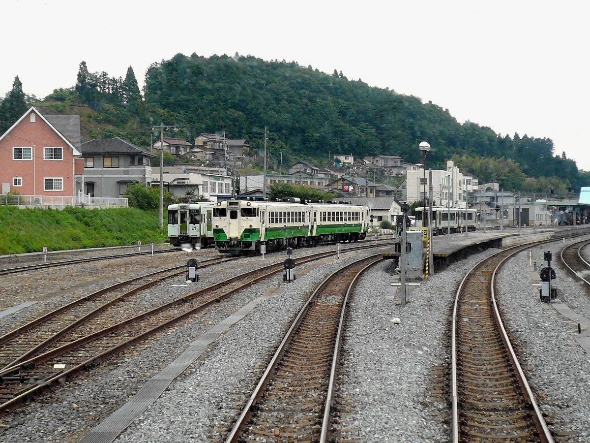 Ôfunato-Linie, Kesennuma einst: In dieser Station waren die beiden Teilstücke der Ôfunato-Linie (die Bergstrecke und die Küstenstrecke nach Norden) miteinander verbunden, während die schmucken grün-weissen Triebzüge der Kesennuma-Linie die Fahrgäste der Küste entlang nach Süden nahmen. Heute nach der Tsunami-Katastrophe (11.3.2011) ist von den Küstenstrecken nichts mehr übrig, und die Station Kesennuma ist ein einsamer Endpunkt geworden. Bild: Einfahrt in Kesennuma am 9.Juli 2010; unter anderem wartet dort eine Komposition der Kesennuma-Linie (KIHA 48 501 - KIHA 48 1511).  