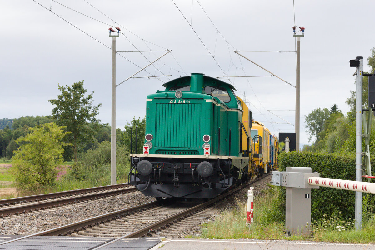 213 339 am Zugschluss eines Bauzugs weiter bestehend aus Stopfmaschine und 215 101 an der Spitze am 08.08.2021 bei Ravensburg in Richtung Süden fahrend. 