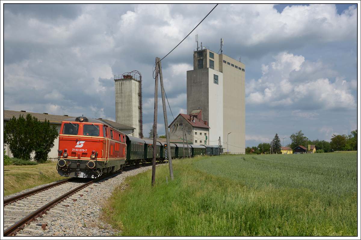 2143 70 vom Verein Neue Landesbahn mit dem Reblausexpress 16972 von Retz nach Drosendorf am 3.6.2018 bei der Ausfahrt aus Langau. Der Bahnhof ist im Hintergrund zu erkenne. 