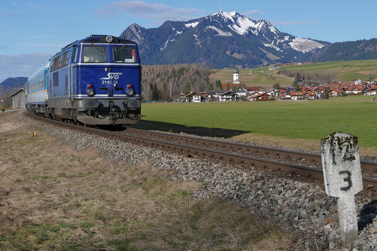 2143.18 der SVG hat eine viertel Stunde zuvor zwei Wagen des von München kommenden Zuges in Immenstadt übernommen und zieht diese als ALX 84158 zum Ziel nach Oberstdorf. Mit Blick auf Altstädten und den 1.738 m hohen Grünten wurde am 21.02.2016 auf den Auslöser gedrückt.