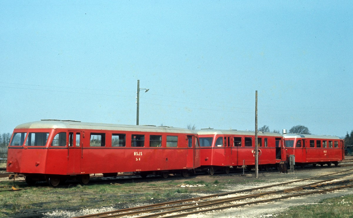 ØSJS (Østsjællandske Jernbaneselskab, Østbanen) am 24. April 1973: Vor dem Depot in Hårlev halten abgestellte Schienenbusse - Sp 6 (Beiwagen; Scandia 1951), Sp ? (Beiwagen mit Gepäckraum; Scandia) und Sm 15 (Triebwagen; Scandia 1952; Frichs-8-Zylinder-Dieselmotor). - Diese Schienenbusse (Triebwagen des Typs Sm, Beiwagen mit / ohne Gepäckraum des Typs Sp und kleine Gepäckwagen des Typs Sb) wurden von der Firma Scandia in Randers (Jütland) ab der Mitte der 40er bis in die 50er Jahre hergestellt. Die letzten Schienenbusse dieser Art fuhren im Jahre 1974 auf der ØSJS (Østbanen). - Das Vorbild lieferten schwedische Schienenbusse aus der 40er Jahre. 1945 mietete die Privatbahn Næstved-Præstø-Mern-Banen (NPMB) einen Zug von der SJ (Sm 1 + Sp 1, ex-SJ Yo1 514 + YCF01 1549; Carlsson 1945). - Kurz danach begann die Firma Scandia eine Produktion von Lizenz-Schienenbussen; die erste Serie wurde an etwa 30 dänische Privatbahnen verkauft. 