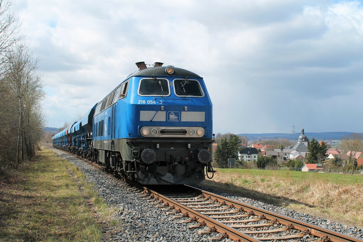 218 054-3 (92 80 1218 448-9 D-PRESS) der PRESS am 10.4.2022 mit einem leeren Schotterzug auf dem Weg von Saalfeld/Saale nach Espenhain. Nach einem Kreuzungshalt verlässt sie hier Oppurg