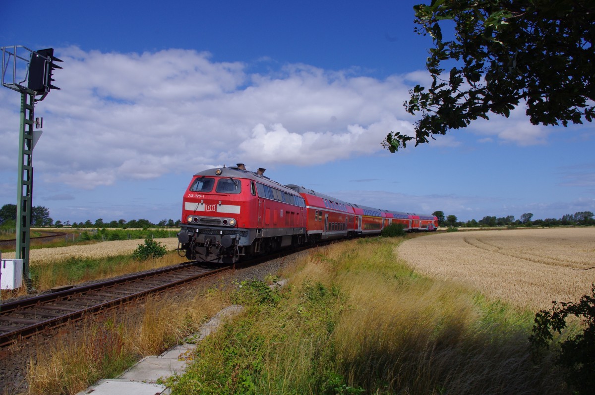 218 329-1 am 26.07.2015 mit dem Hamburg-Strand-Express bei der Einfahrt in den Bahnhof Fehmarn-Burg, aus Richtung Puttgarden kommend.