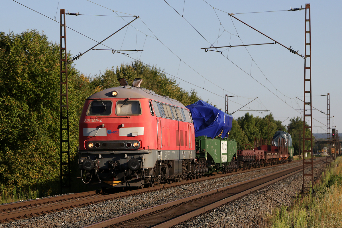 218 399 der ELBA Logistik befördert am 06.08.2020 zwei Schiffsdiesel durch das Maintal, aufgenommen bei Thüngersheim