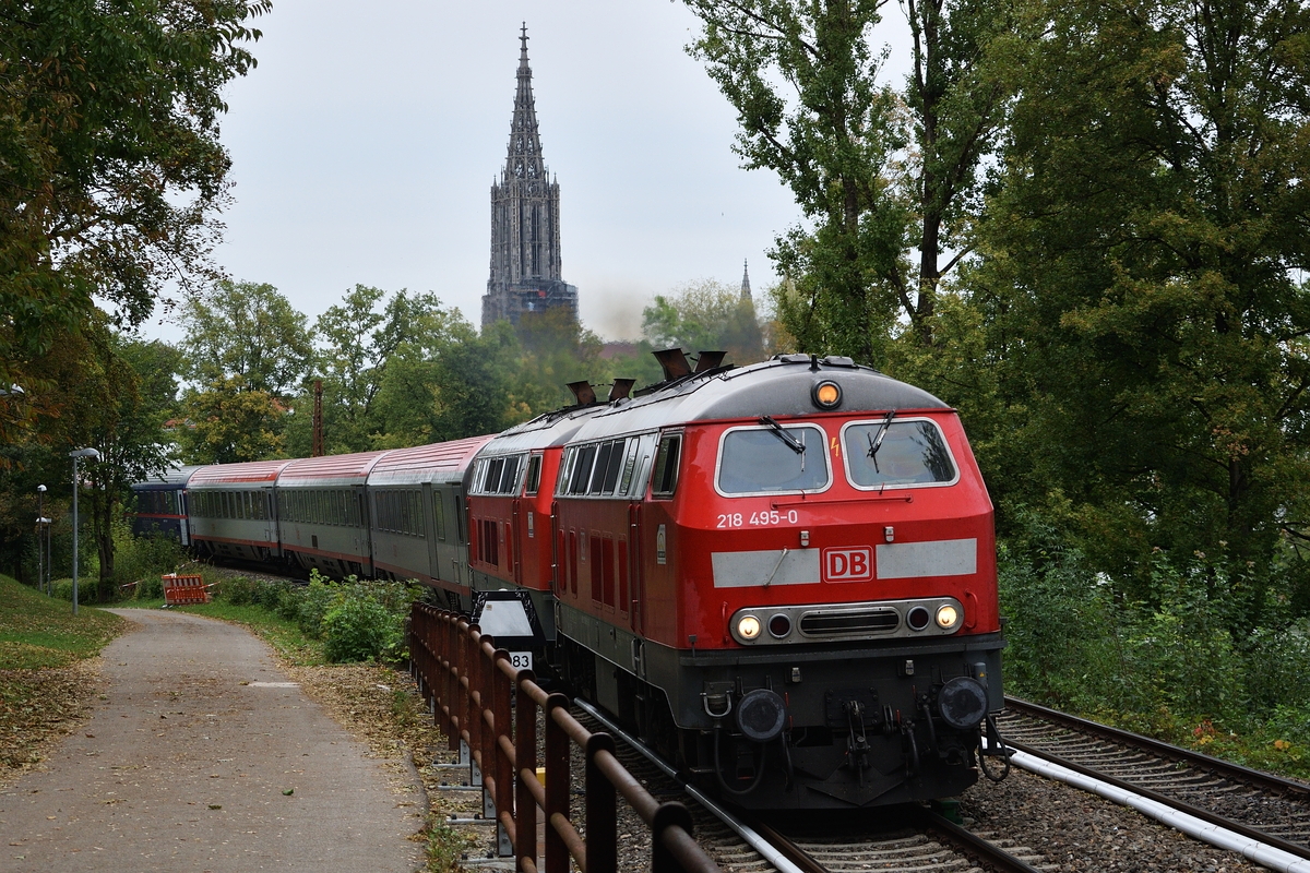 218 495 und eine Schwester bespannen am 1. September 2018 IC 119, hier kurz nach der Ausfahrt aus Ulm Hbf. Im Hintergrund ist das Ulmer Münster zu erkennen.