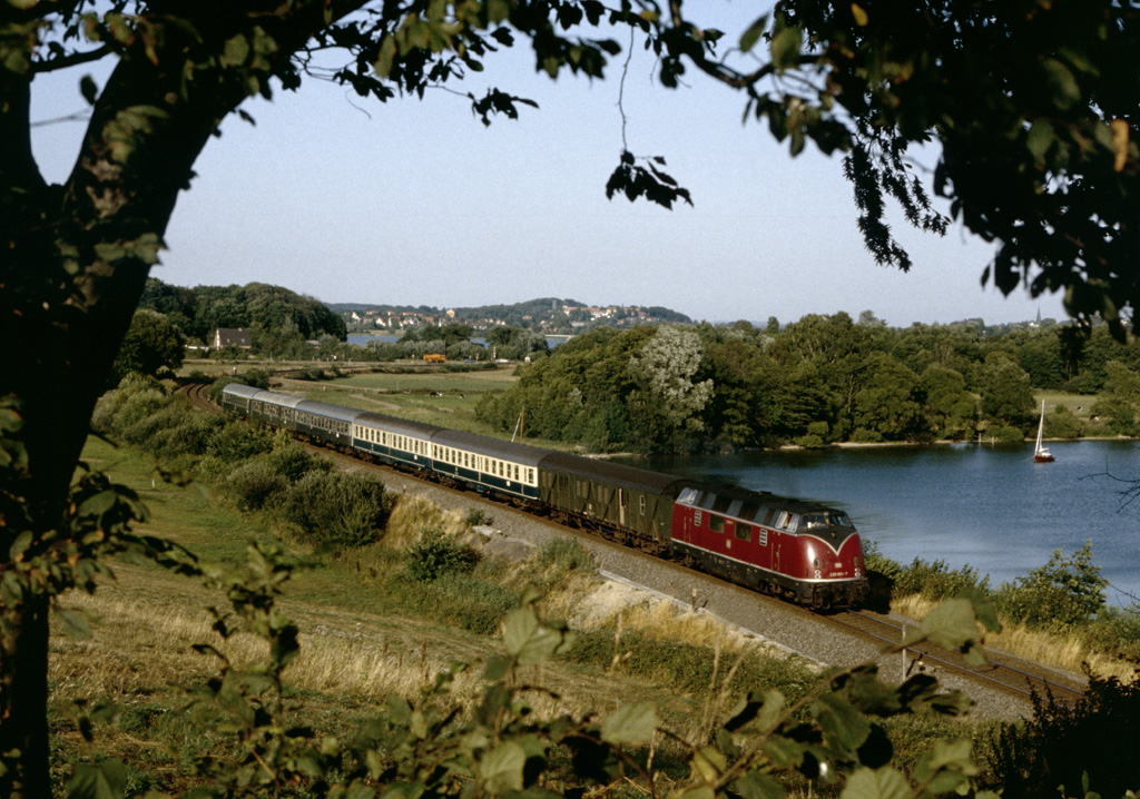 220 051 mit Eilzug nach Kiel am 11.8.1983 am Plner See. Am Schlu des Zuges laufen zwei DR-Kurswagen.