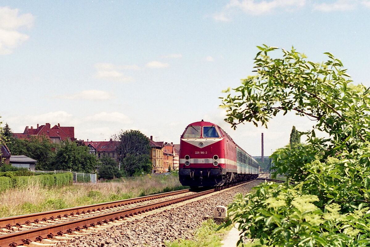 229 186-2 fährt im Juni 1997 mit ihrem RE aus Mühlhausen aus. Das hier unter dem letzten Wagen abzweigende Gleis endete direkt hinter dem Busch an einem Prellbock, früher ging es dort weiter in die Industrieanschlüsse, die Weiche ist heute ausgebaut. Negativ Scan 