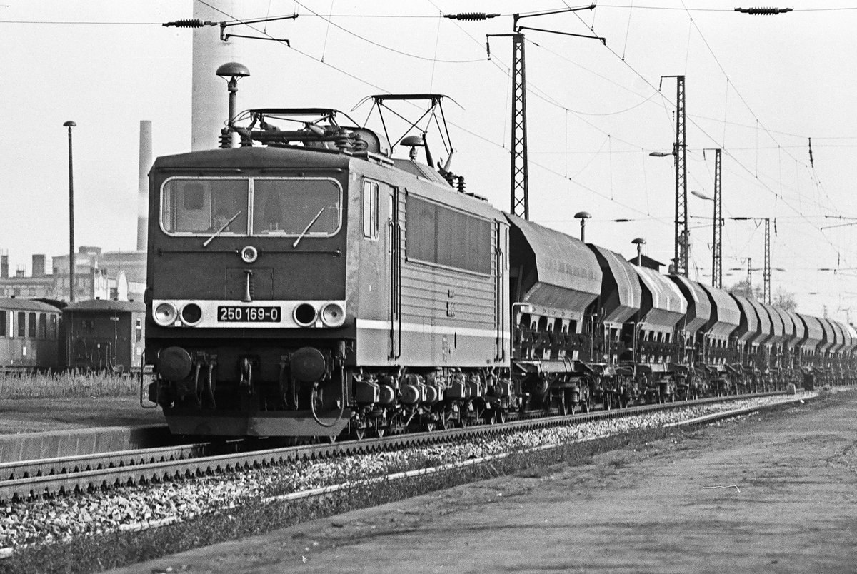 23. Oktober 1982, Lok 250 169 fährt mit einem Güterzug in Richtung Berlin/Leipzig durch den Bahnhof Radebeul Ost. Im Hintergrund sind Fahrzeuge der Schmalspurbahn nach Radeburg zu erkennen.