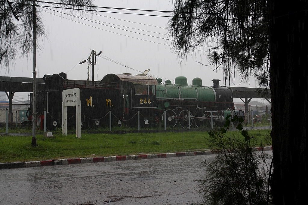 244 (2'C1'-h3, Baldwin, Bauj. 1928, Fab.Nr. 60410) aufgestellt beim der Hat Yai Junction am 07.Jänner 2023.  -  Da fliegt man extra nach Hat Yai um die Reste der Songkhla-Line zu fotographieren, ist 48 Stunden dort und hat davon 44 Stunden Regen. Statt eines Motorades mietet man dann ein Taxi mit einem älterem Fahrer, (man denkt ja der kann sich noch an die Bahnlinie erinnern) und dieser fragt dann in Songkhla 200 Meter vor dem alten Bahnhof Passanten nach dem Weg. 100 Meter vor dem Hotel gab dann das Taxi den Geist auf (Wasser im Tank), sodass dieses Bild von einem Imbisslokal aus gemacht wurde.