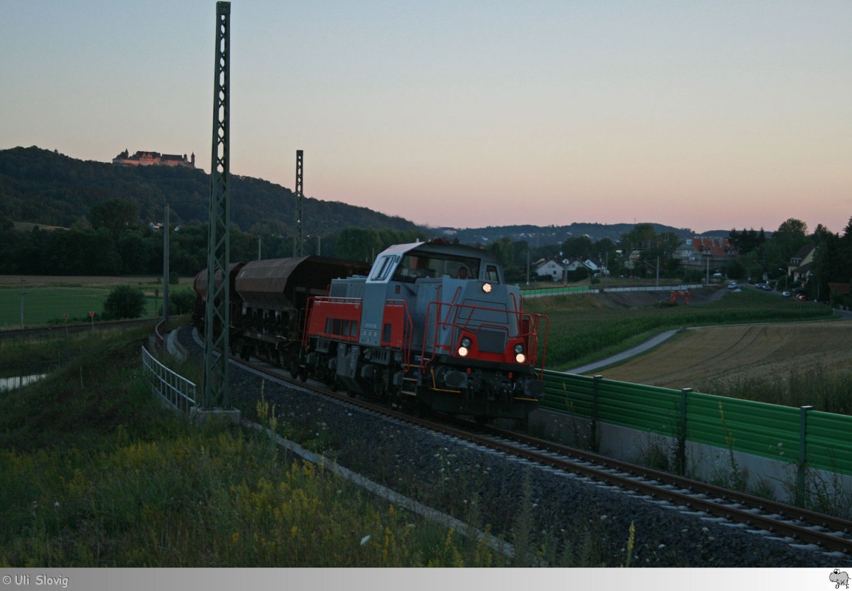 261 309-9 der SGL zieht im letzten Tageslicht des 21. Juli 2015 einen Schotterzug über die Rampe zur Neubaustrecke Nürnberg-Erfurt bei Dörfles-Esbach (Landkreis Coburg).