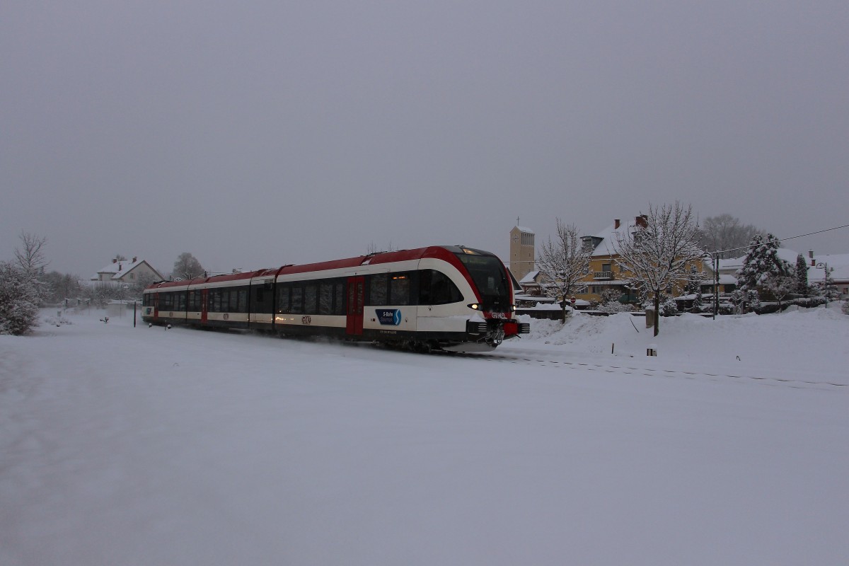 28. Dezember 2014. GTW 07 als R8594 bei Pölfing Brunn. Die erst ab 1955 errichtete Pfarrkirche  Maria Königin  im Hintergrund wacht über den in den letzten Jahren öfters in den Medien vertretenen Ort. 
