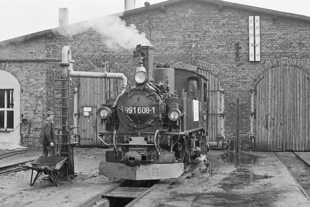 29. September 1984, Schmalspurbahnhof Mügeln. Die Mügelner Schmalspurbahn feierte an diesem Wochenende ihr 100-jähriges Bestehen. Gleichzeitig konnte die Stadt Mügeln auf eine 1000-jährige Geschichte zurückblicken. Verschwiegen wurde auch nicht, dass auch die DDR ein rundes Jubiläum feierte, sie wurde vor 35 Jahren gegründet. Schilder und Fähnchen wiesen an den Lokomotiven auf diese Ereignisse hin. Lok 99 608 nimmt Wasser.