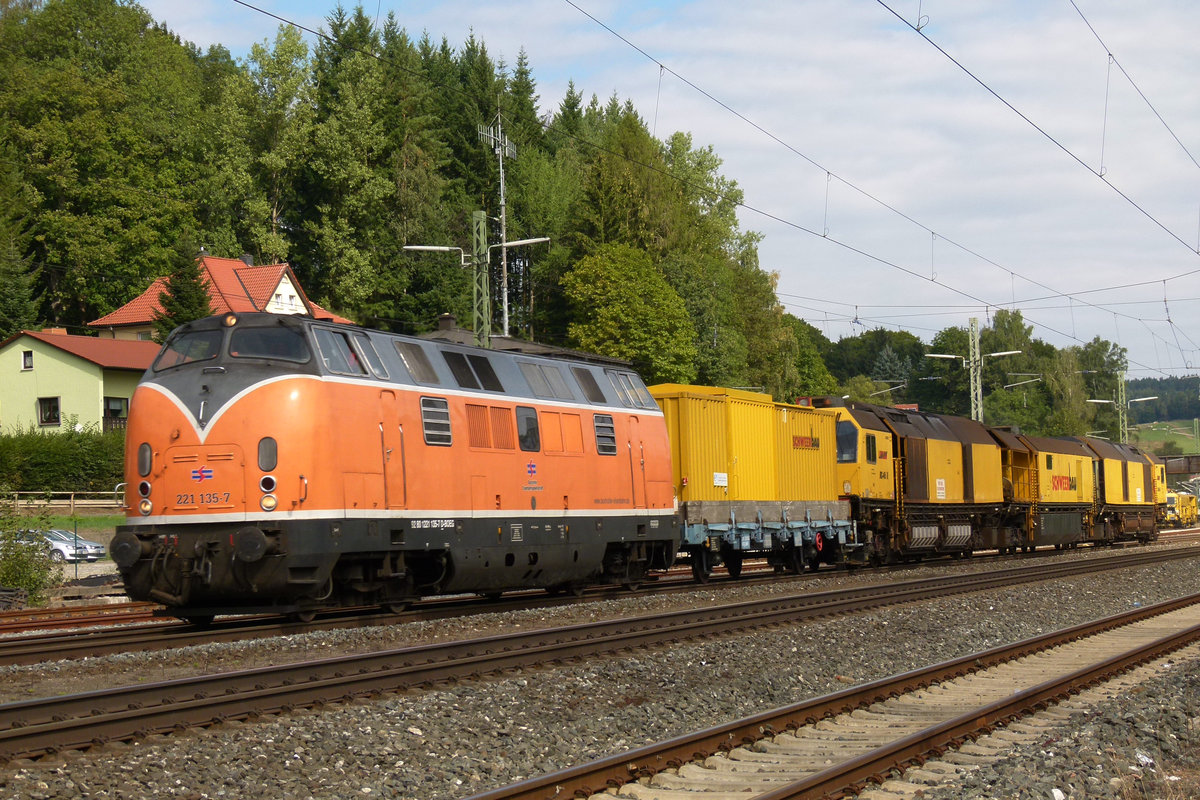 31. August 2011: Ein farbenfrohes Gespann. Lok 221 135, im Eigentum der Bocholter Eisenbahn fährt, aus Richtung Saalfeld kommend, mit der Schienenschleifmaschine RG48 I und II der SchweerBau durch den Bahnhof Kronach