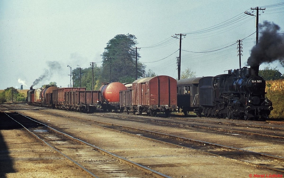 324.1551 und (im Hintergrund) 324.1581 im Oktober 1978 im Bahnhof Veszpremvarsany, Kreuzungspunkt der Strecken von Gyr nach Veszprem und von Papa nach Tatabanya. Whrend die erstgenannte Strecke schon weitgehend verdieselt war, beherrschten die 324 den sprlichen Verkehr auf der Bahnlinie von Papa nach Tatabanya. Diese 1'C1'h2-Lokomotiven wurden (zunchst als Nassdampflokomotiven) zwischen 1909 und 1923 fr den Schnellzugdienst (Hchstgeschwindigkeit 75 km/h) geliefert, spter wanderten sie in den Nebenbahndienst ab.