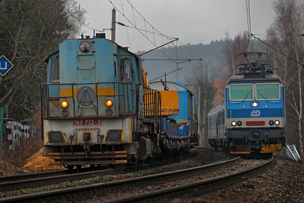 363 054-8 fährt mit einem Schnellzug aus Prag an der 740 732-3 vorüber,die mit einem Bauzug beschäftigt ist neue Fahrleitungsmasten Ausgangs Pilsen aufzurichten.Bild vom 13.2.2015 