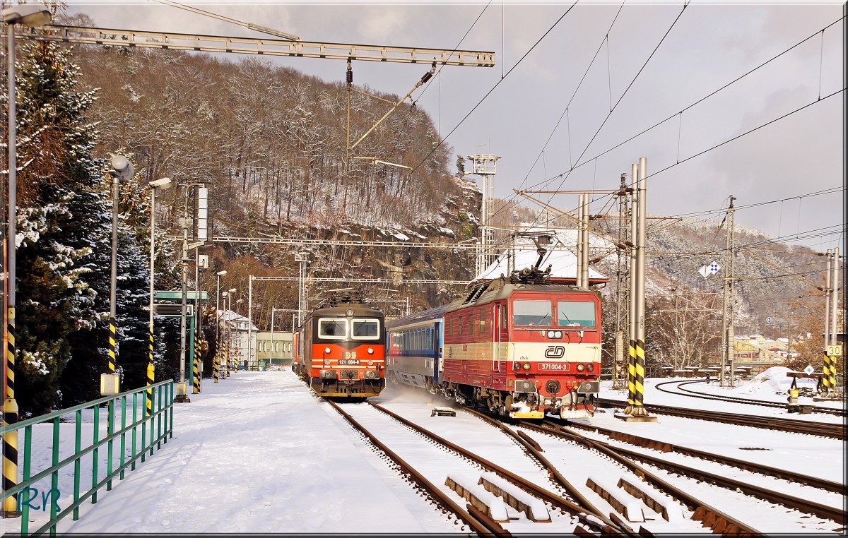 371 004 fährt aus Deutschland kommend in den Bahnhof von Decin ein. Links steht die 121 084 vom Privaten Bahnunternehmen IDS. Aufgenommen am 18.01.2016.