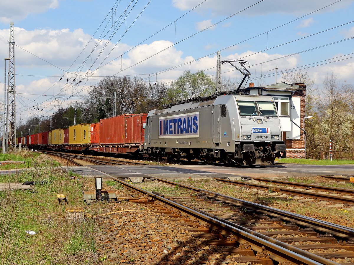 386 004-6 von der METRANS mit einem Containerzugam 21. April 2021 bei der Überfahrt des Bahnübergang Zossen (Brandenburg). Standort in der Strasse An den Wulzen, Zossen. Geht ab von der B 246.

