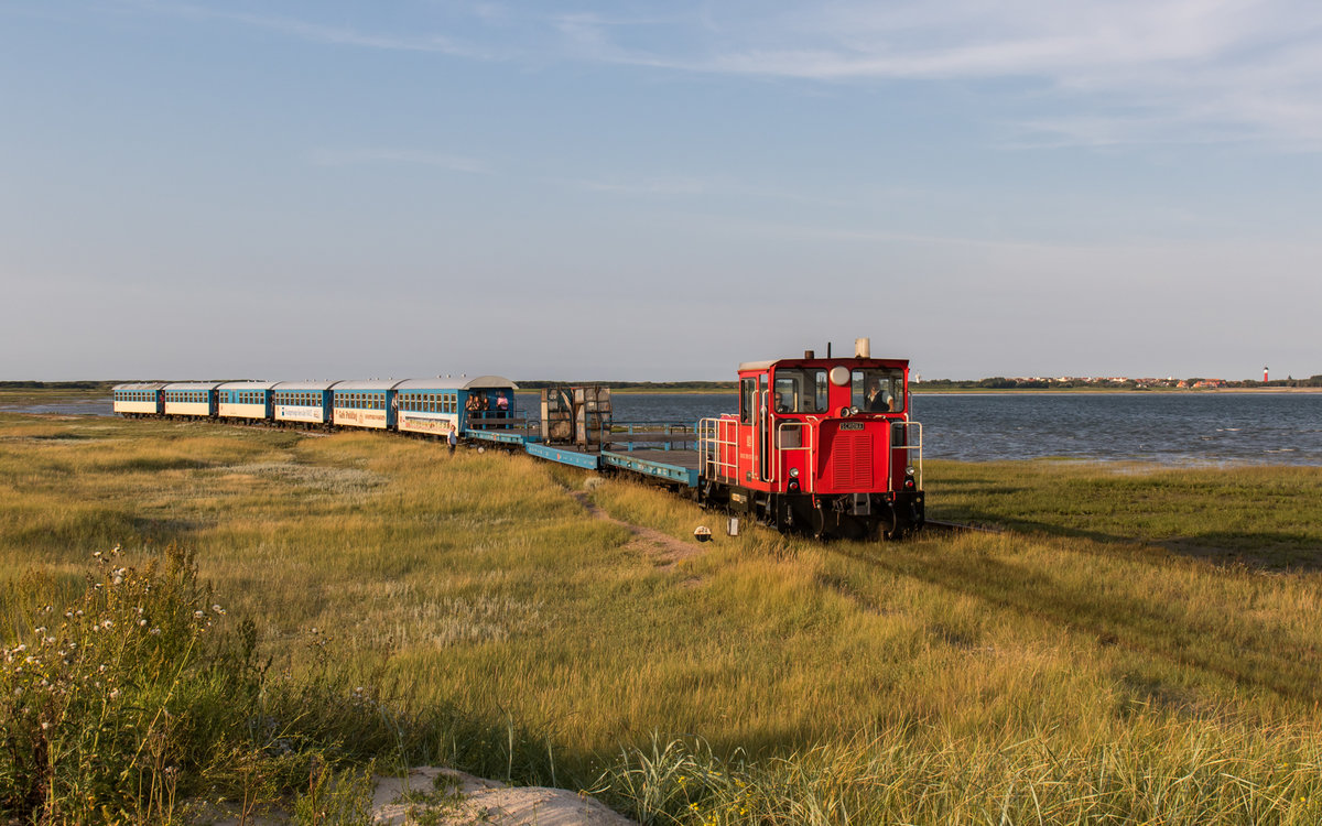 399 107 fährt mit einigen Güter- und Personenwagen zum Westanleger, um anschließend die letzten Anreisenden sicher ins Zentrum von Wangerooge zu befördern. Aufgenommen am 27. August 2016.