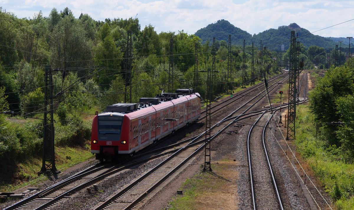 425 133 ist als RB von Homburg nach Trier unterwegs und hat gerade den Bahnhof Bous verlassen. Auf der rechten Seite sind die Übergabe- und Anschlussgleise der Stahlwerke Bous zu sehen. Zu Zeiten der Mannesmann Röhrenwerke herrschte hier Hochbetrieb. Im Hintergrund erkennt man die Halden  Hermann und Erika , die nach den Vornamen des Ehepaars Röchling benannt sind. Dies sind Schlackenhalden der ehemaligen Röchling´schen Eisen- und Stahlwerke in Völklingen. 15.06.2014 - Bahnstrecke 3230 Saarbrücken - Karthaus.