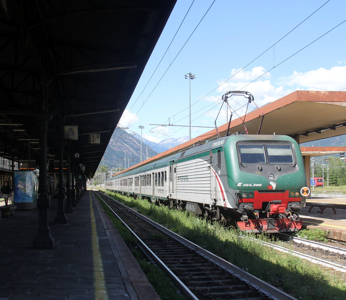 464 396 steht im Bahnhof von Domodossola(I) mit einem italienischer Regionalzug von Domodossola(I) nach Milano-Centrale(I). 
Aufgenommen von Bahnsteig in Domodossola(I).
 Bei Sommerwetter am Nachmittag vom 29.7.2019.