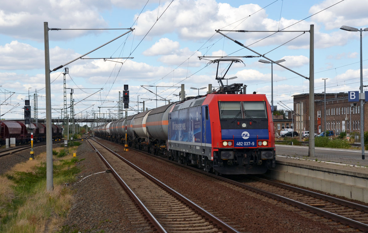 482 037 der Infra Leuna schleppte am 26.08.18 einen Zug Gaskesselwagen von Wittenberg-Piesteritz nach Großkorbetha durch Bitterfeld Richtung Leipzig. Links schiebt eine G6 der RBB gerade Wagen in den Güterbereich.