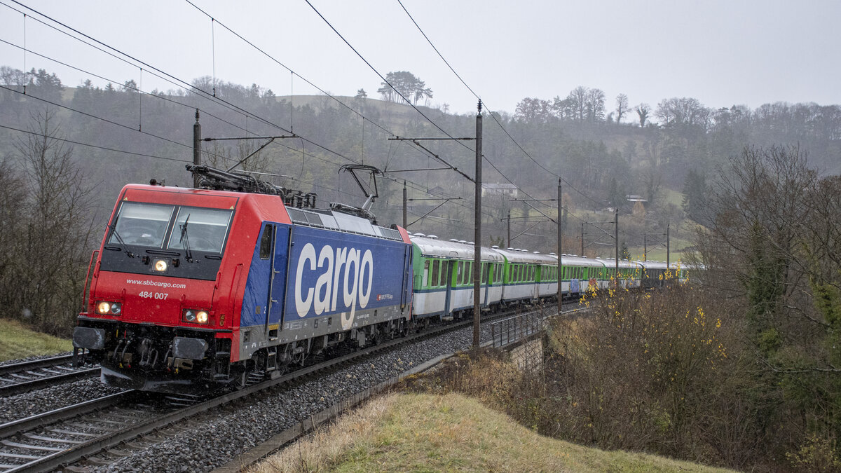 484 007 ist mit dem VerbanoExpress aus dem Süden kommend nach Basel an den Weihnachtsmarkt unterwegs. Aufgenommen im Regen bei Villnachern AG (CH) am 27.11.2021.