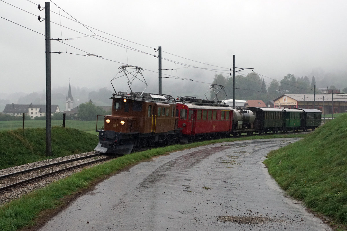 50 Jahre Blonay Chamby - MEGA BERNINA FESTIVAL
Büdnertag im Saanenland
1968-2018 50 JAHRE
BLONAY-CHAMBY
CHEMIN DE FER-MUSEE
Der Büdnertag im Saanenland vom 14. September 2018 begann leider bei sehr schlechtem Wetter.
Zug 2 bespannt mit der RhB Ge 4/4 182 und dem BC ABe 4/4 35, ehemals RhB, bei Lessoc auf der Fahrt nach Bulle. Zum Zeitpunkt dieser Aufnahme regnete es sehr stark, was die Allwetterfotografen nicht abschreckte.
Besondere Beachtung gilt dem hinter den Triebfahrzeugen eingereihten Kesselwagen.    
Foto: Walter Ruetsch 