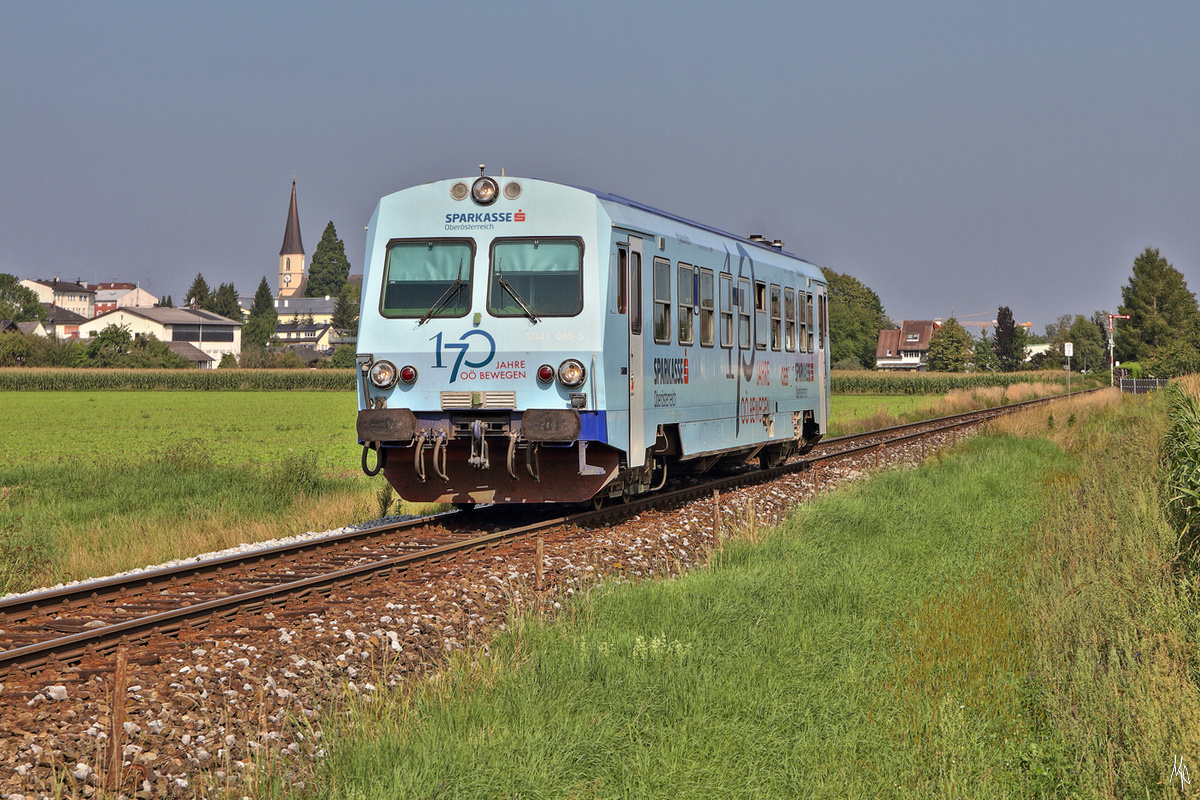 5047.085 auf der Fahrt von Braunau nach Steindorf bei Straßwalchen. Links neben dem Triebwagen erkennt man die Pfarrkirche von Mattighofen, am rechten Bildrand das Einfahrsignal des Bahnhofs. (24.08.2019)