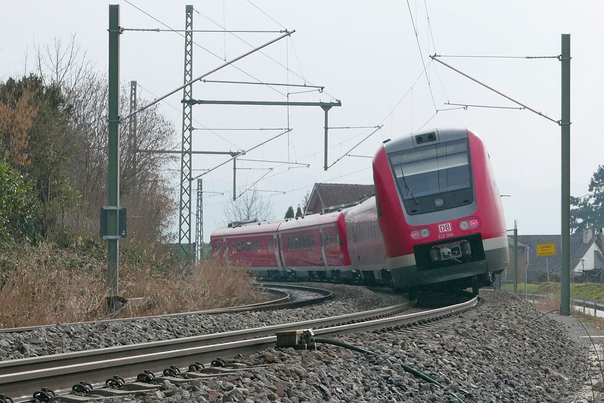 612 004 und ein weiterer Triebwagen der Baureihe 612 am 10.03.2021 als RE 7 / RE 3285, Lindau-Reutin - Augsburg, in der Nähe des Lindauer Ortsteils Schönau. Aufnahmestandort die am rechten unteren Bildrand zu sehende Straße, die in einem ähnlichen Bogen verläuft wie die Gleise.