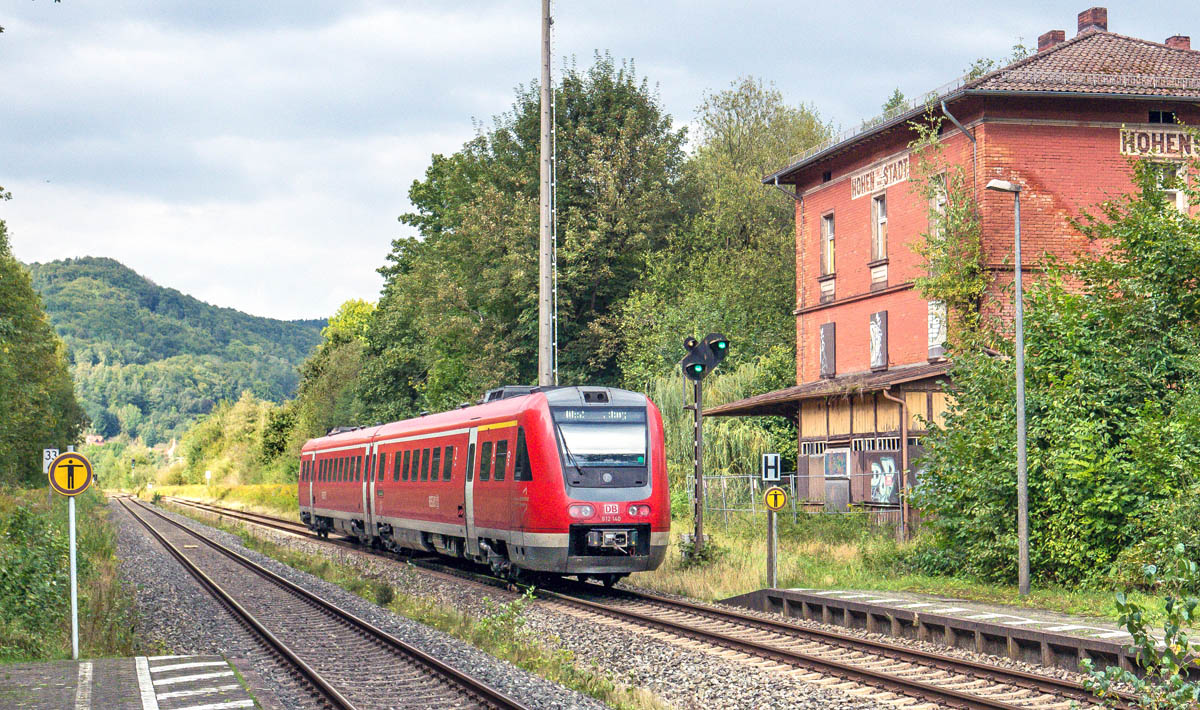 612 140 fuhr am 17.9.24 solo am alten Empfangsgeb�ude von Hohenstadt und dem Ausfahrvorsignal vorbei nach Bayreuth. Bemerkenswert ist, dass der Der Name „Hohen–stadt“ auf der Gleisseite ohne Platznot getrennt wurde.
[Neue Version vom 21.6.25, Rauschen entfernt.]