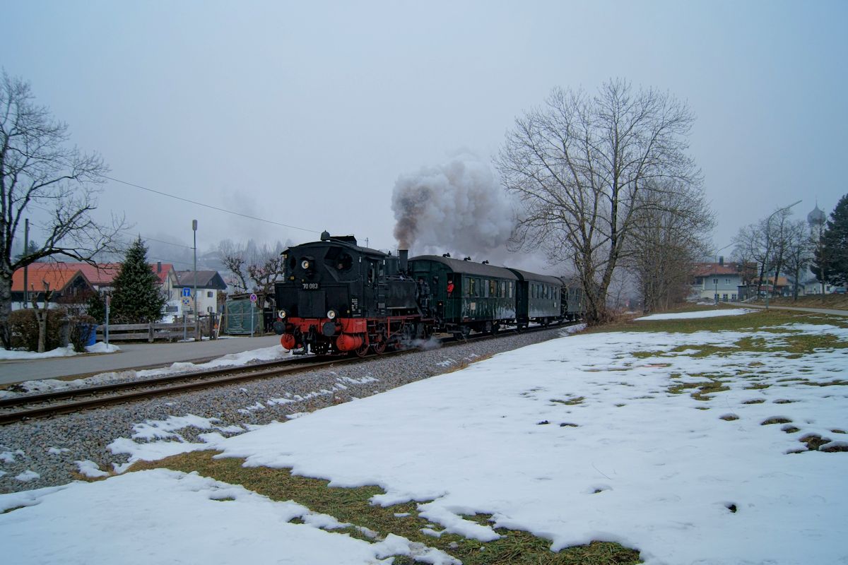 70 083 des bayerischen Localbahn Vereins war am 12.02.2017 mit einem Dampfzug zwischen Holzkirchen und Tegernsee unterwegs. Hier durchfhrt der Zug den Ort Gmund am Tegernsee. Whrend das Wetter in den tieferen Lagen sehr trb war, schien in Tegernsee die Sonne.
