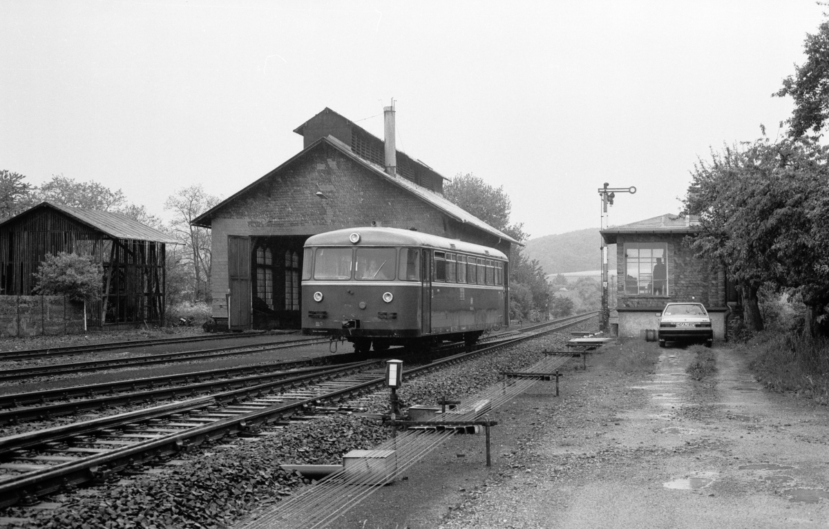 795 634 setzt vor Modellbahnkulisse in Gestalt von Stellwerk, Signal und Lokschuppen in Grävenwiesbach am 29.5.1980 um.