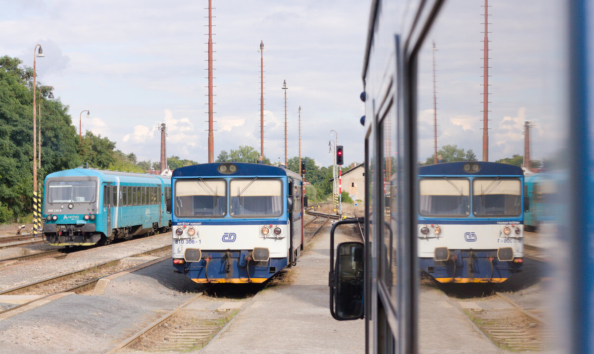845 116+xxx als R25 nach Praha Mas. n. und 810 306 am 27.08.2021 im Bahnhof Hostivice. Ein Teil der Szenerie spiegelt sich in der mitsamt Fotografen abfahrenden Regiomaus wider. 