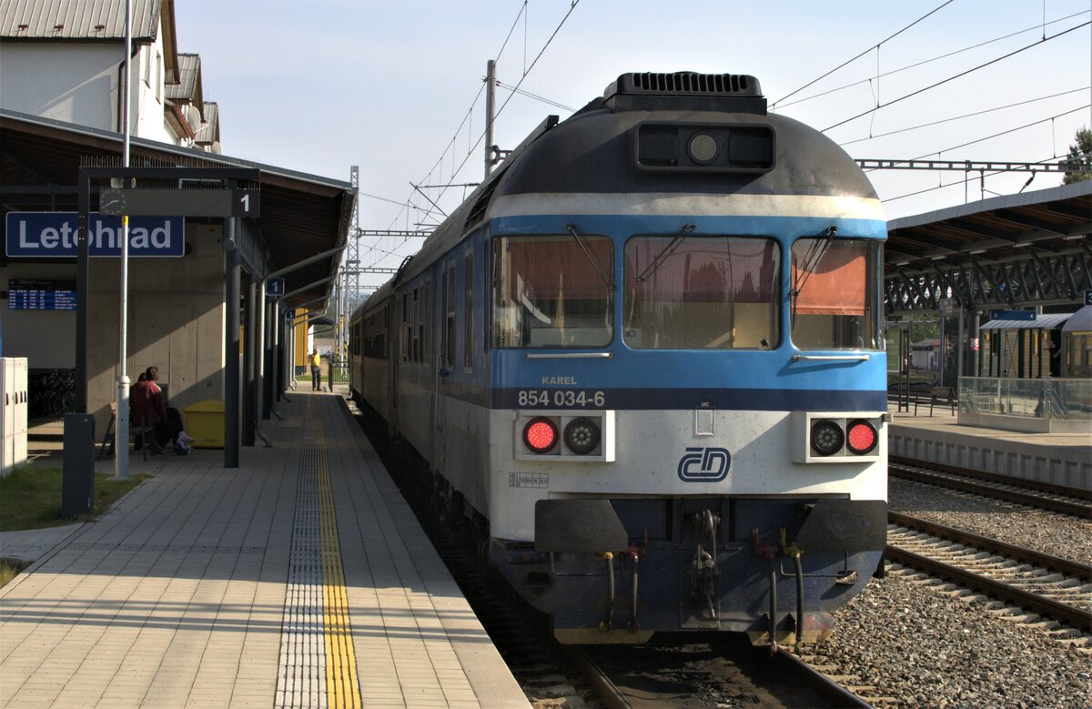 854 034-6  Karel  soeben aus Hradec Králové (deutsch Königgrätz).eingelaufen.
02.10.2021 14:44 Uhr. Vor der Abfahrt 11:33 Uhr als
Eilzug
Sp 1830
1.2.pL©
České dráhy, a.s.  nach Hradec Králové hl.n., hatte der Fotograf, mit einem DB Cargo Lokführer , welcher auf der Strecke Dresden-Lovosice unterwegs ist, reisend, eine Führestandsbesichtigung zu erleben. Die TW der Baureihe 854 sind robust, beim Personal beliebt, die V max  beträgt 120 Km/h. Selbige  wird im Solobetrieb locker erreicht, mit 2 Wagen, im Hügelland  sind es immehin noch bis 90 km/h.
Die Geschwindigkeit kann an einem Tastenpult  vorgewählt werden und wird auch in Steigungen fast konstant gehalten. Ein Kühlschrank ist im Führestand, die TW sind  schon 2x modernisiert worden und werden wohl noch einige Jahre im Einsatz bleiben.
Letohrad, 02.10.2021 14:43 Uhr.