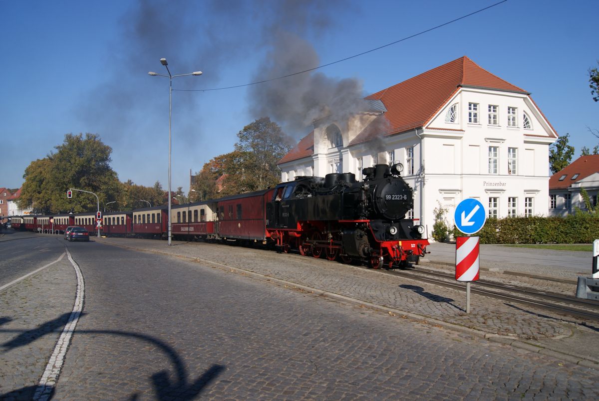 99 2323 ist am 10.10.2015 mit einem Personenzug auf dem Weg von Kühlungsborn nach Bad Doberan den Alexandrinenplatz am Zielort.
