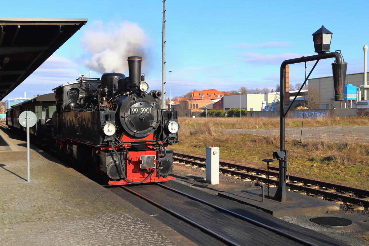 99 5901 mit IG HSB-Sonder-PmG am Nachmittag des 26.02.2017, nach Ende der Veranstaltung, im Bahnhof Quedlinburg. Da noch Wasser genommen und die Einfahrt eines Plantriebwagens abgewartet werden muß, wird in wenigen Augenblicken auf Gleis 2 umgesetzt. Noch ein paar Worte zu dem grauen Kasten in der Bildmitte: Der ist zwar nicht schön, aber notwendig, denn in ihm befindet sich die Schaltung für die elektrische Förderpumpe des Wasserkranes. Ob man das Teil nicht hätte etwas gefälliger gestalten können, eben gerade WEIL das Ensemble Dampflok und Wasserkran ein beliebtes Fotomotiv darstellt, ist eine andere Frage!