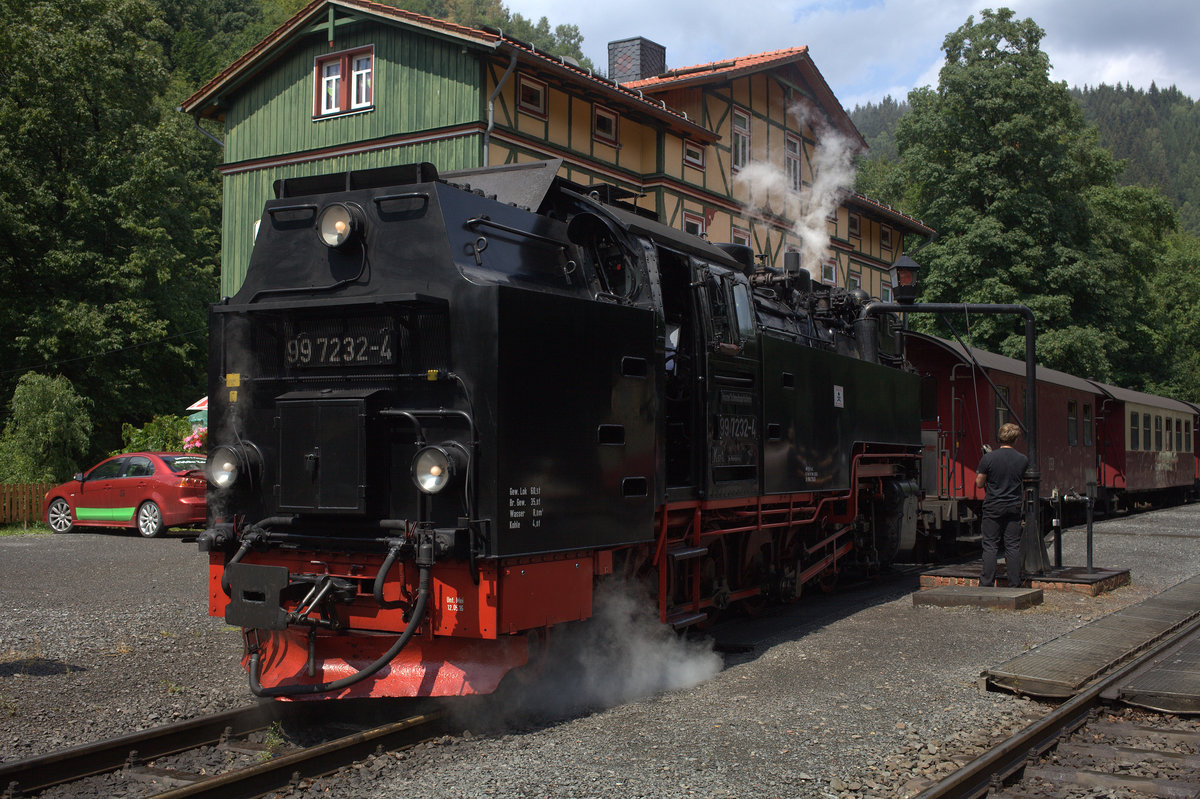 99 7232-4, hier  beim Wassernehmen, befördert den Personenzug  8903 , 11:55 Uhr ab Wernigerode nach Eisfelder Talmühle von Drei Annen Hohne bis Eisfelder Talmühle und wieder zurück nach Drei Annen Hohne. Hier kurz nach der Ankunft aus Drei Annen Hohne, es bleibt für Lok - und Zugpersonal Zeit für ein kurzes Mittagessen, für die Führestandsmitfahrer Zeit für einen Kaffee, bevor sie den Zug 8904  14.08 Uhr in Eisfelder Talmühle wieder übernimmt. 14.07.2018  13:50 Uhr.