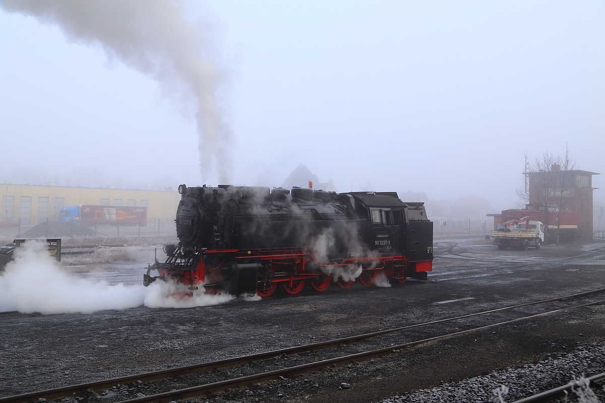 99 7237 am Morgen des 13.02.2015 im Bw Wernigerode beim Durchblasen der Zylinderentwässerungen. Am Stellwerk rechts hinten wartet eine unbekannte 199 auf ihren nächsten Einsatz , unmittelbar davor ist der kleine LKW zu sehen, welcher die Dampfloks auf langen Sonderfahrten mit Kohlenachschub versorgt.