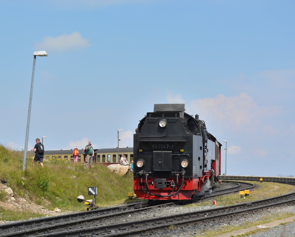 99 7247-2 dampft mit einem Zug aus dem Bahnhof Brocken wieder den Brocken hinunter. Das Spektakel der Ausfahrt der Dampfzüge wird von vielen Besuchern gefilmt oder bildlich festgehalten. 

Brocken 22.07.2016