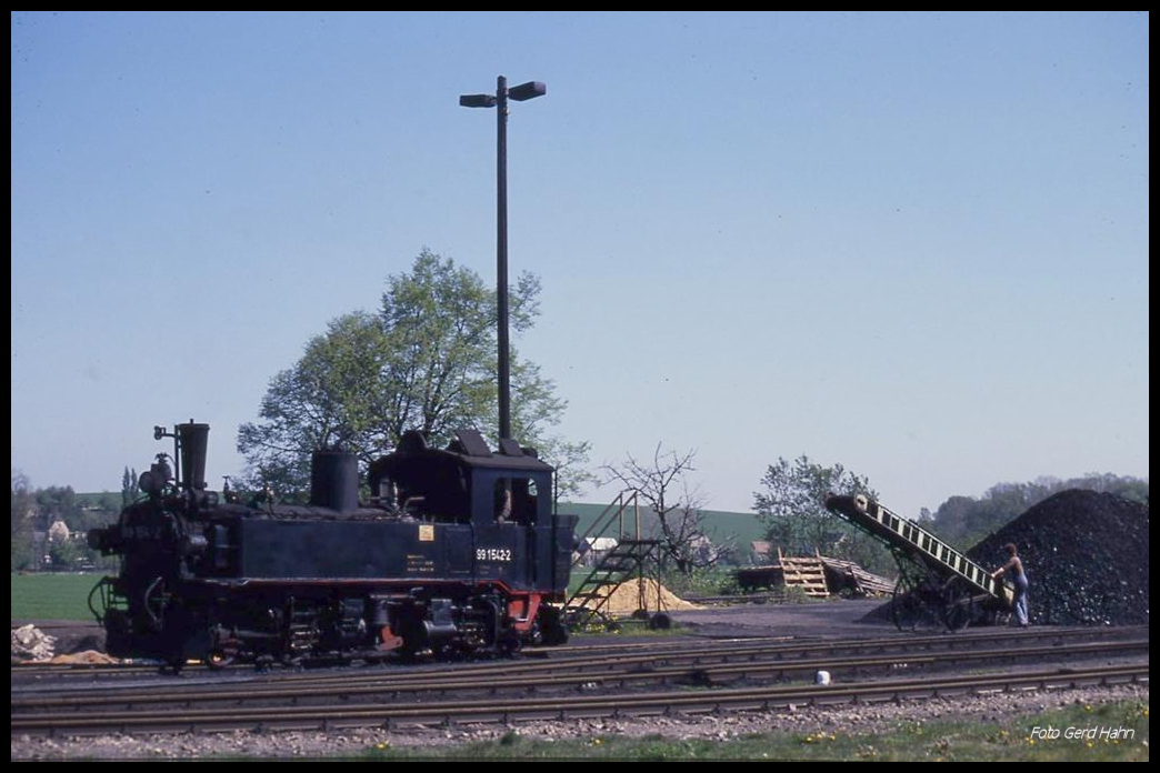 991542 rollt am 3.56.1990 im Bahnhof Mügeln zum Bekohlen. Die Dame in Latzhose wartet bereits auf ihren Einsatz am Förderband.
