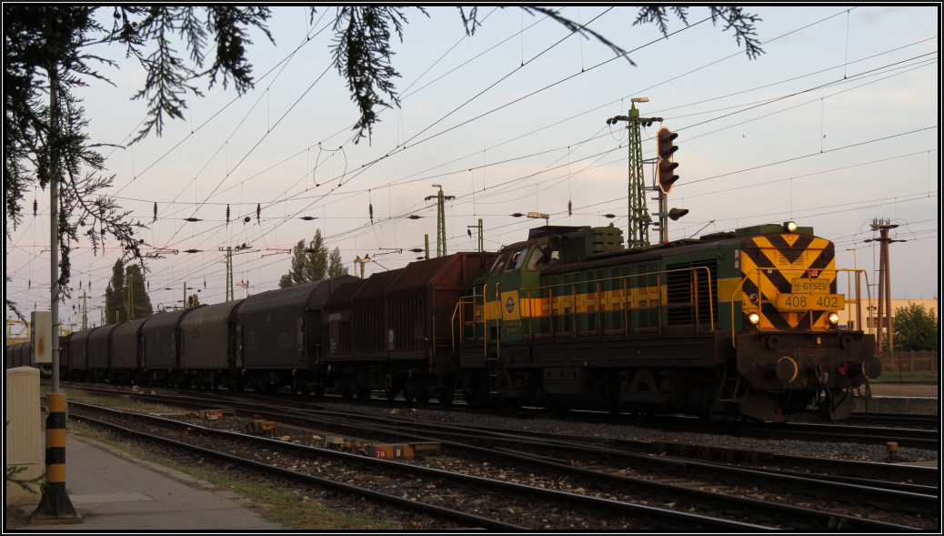 Abendstimmung am Bahnhof von Komárom (H) am 05.August 2015. Ein heißer Tag neigt sich dem Ende entgegen. Derweil macht sich die 408 402 der Gysev (Raaberbahn) im letzten Sonnenlicht mit einen Coilzug nach Györ auf.