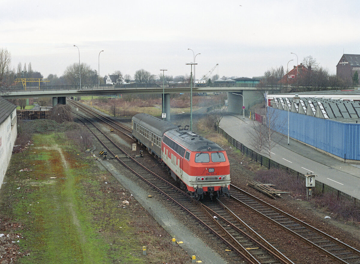 Abfahrt des E-3784 (Kleve - Nijmegen) aus Kleve am 10.02.1990. Ein BDnf735 vorne, DB 218 140-2 (in der Orangenen CityBahn Farbe) schiebt. Rechts zweigte die ehemalige Strecke von Kleve nach Spyck ab, deren Trassenverlauf man noch gut erkennen kann. Scanbild 208.7757, Kodak Ektacolor Gold.