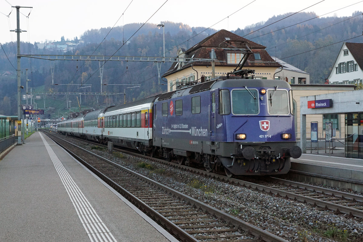 Abschied von den EC Zürich-HB  - München mit den Re 421 und den BR 218 sowie  dem alten Kopfbahnhof  Lindau vor dem Fahrplanwechsel vom 13. Dezember 2020.
Der Fahrplan 2021 bringt schnellere, häufigere und bequemere Verbindungen von Zürich-HB nach München. Die dunkelblauen Re 421 von SBB CARGO NATIONAL und die DB Diesellokomotiven der BR 218 werden nicht mehr gebraucht.  Auch der Lokwechsel im alten Kopfbahnhof Lindau mit dem schmucken Gebäude ist  bereits ab dem heutigen Sonntag Geschichte, da die Insel mit den direkten Zügen nicht mehr angefahren wird.
Für einen kurzen Rückblick auf diese herrlichen Momente drehe ich das Rad der Zeit noch einmal für drei Bahnbildserien zurück.
Sämtliche Aufnahmen  sind während meiner Abschiedsfahrt vom 18. November 2020 entstanden. Da es sich um meine letzte Fahrt handelte und die Aufnahmen  inzwischen  bereits historisch sind, habe ich mir ausnahmsweise  erlaubt,  auch der nächtliche Beginn dieser für mich sehr speziellen Reise in Zürich-HB zu zeigen.

EC München - Zürich-HB mit der Re 421 371-6  anlässlich der Bahnhofsdurchfahrt Rheineck im allerletzten Tageslicht.
Foto: Walter Ruetsch
   
