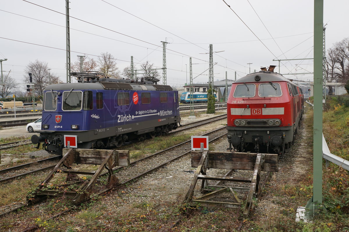 Abschied von den EC Zürich-HB  - München mit den Re 421 und den BR 218 sowie  dem alten Kopfbahnhof  Lindau vor dem Fahrplanwechsel vom 13. Dezember 2020.
Der Fahrplan 2021 bringt schnellere, häufigere und bequemere Verbindungen von Zürich-HB nach München. Die dunkelblauen Re 421 von SBB CARGO NATIONAL und die DB Diesellokomotiven der BR 218 werden nicht mehr gebraucht.  Auch der Lokwechsel im alten Kopfbahnhof Lindau mit dem schmucken Gebäude ist  bereits ab dem heutigen Sonntag Geschichte, da die Insel mit den direkten Zügen nicht mehr angefahren wird.
Für einen kurzen Rückblick auf diese herrlichen Momente drehe ich das Rad der Zeit noch einmal für drei Bahnbildserien zurück.
Sämtliche Aufnahmen  sind während meiner Abschiedsfahrt vom 18. November 2020 entstanden. Da es sich um meine letzte Fahrt handelte und die Aufnahmen  inzwischen  bereits historisch sind, habe ich mir ausnahmsweise  erlaubt,  auch der nächtliche Beginn dieser für mich sehr speziellen Reise in Zürich-HB zu zeigen.

Gemeinsam auf den nächsten Einsatz wartend. SBB Re 421 und DB BR 218.
Foto: Walter Ruetsch
   
