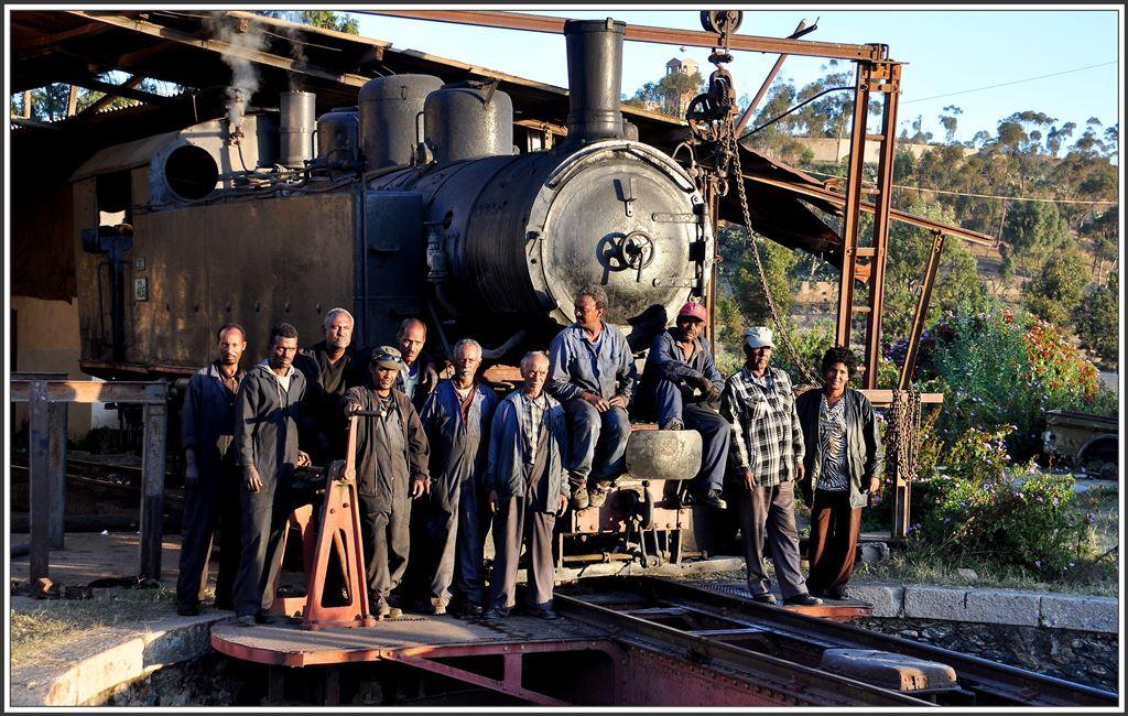 Abschiedsbild der diesjährigen Eritreareise. Die Gruppe der Mitarbeiter hat sich verändert und verkleinert, aber sie gaben alles um einen einigermassen authentischen Betrieb zu zeigen.Schwere Regenfälle haben der Strecke an mehreren Orten zugesetzt und der Fahrzeugpark rostet still und leise vor sich hin und hat mit diesen Fahrten wohl das Ende der Betriebsfähigkeit erreicht. Depot Locomotiva Asmara (12.12.2014)